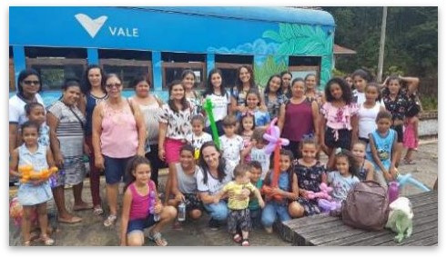 Several women and children pose for a photo in front of the Vale train.