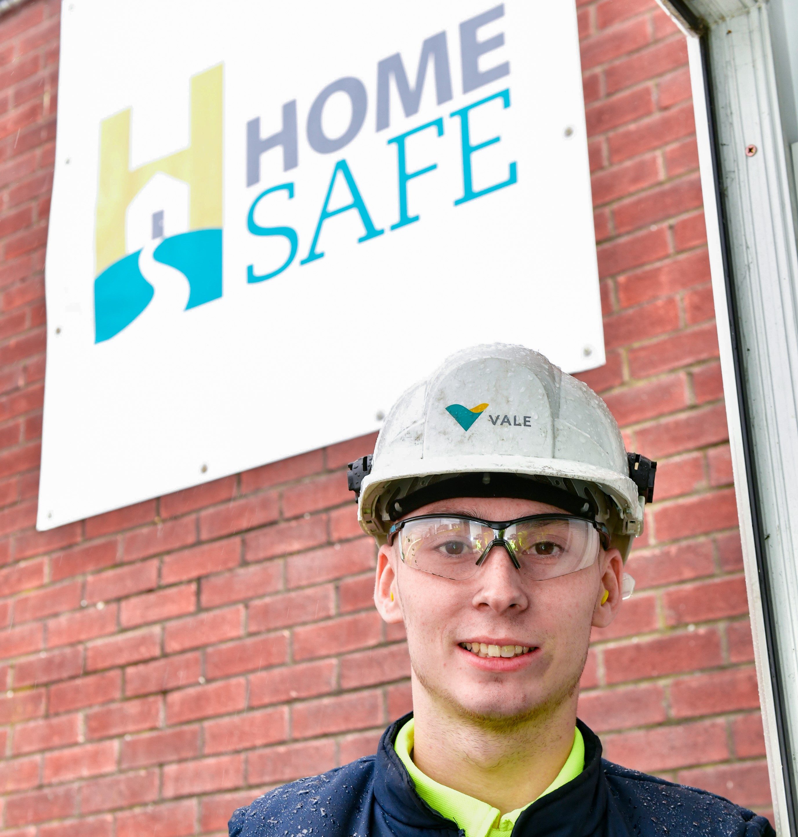 Vale's emploeey with goggles and helmet in front of a "home safe" poster