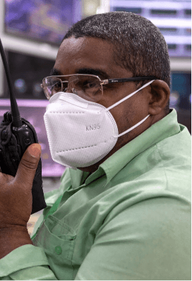 A Vale employee, wearing glasses and a mask, is talking into a radio transmitter.