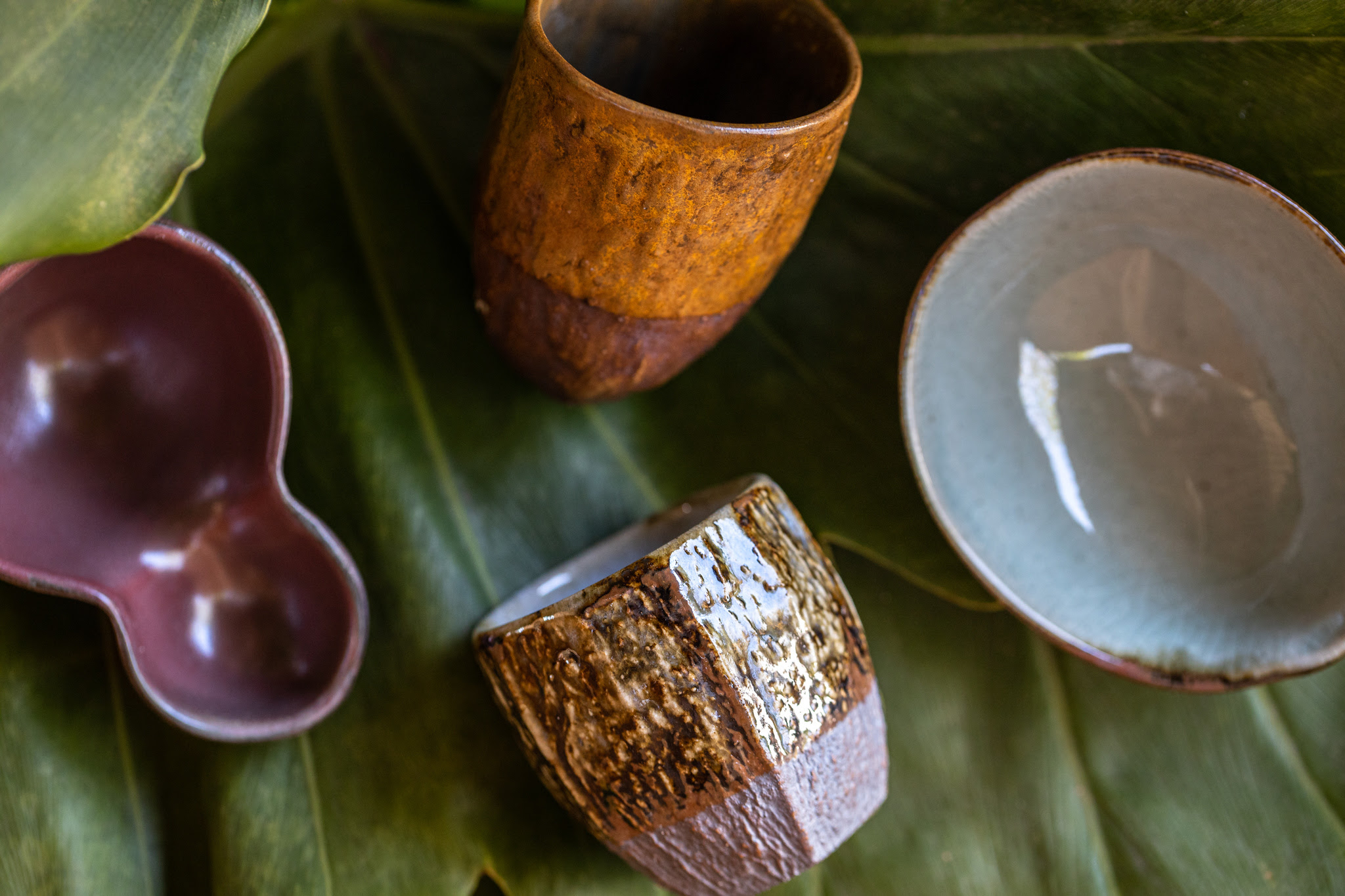 Imagem de quatro potes de cerâmica e, ao fundo, uma folha de árvore.
