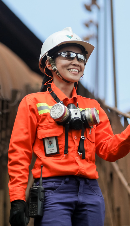 A woman wears a Vale uniform, goggles, helmet and other protective gear as she poses smiling for a photo.