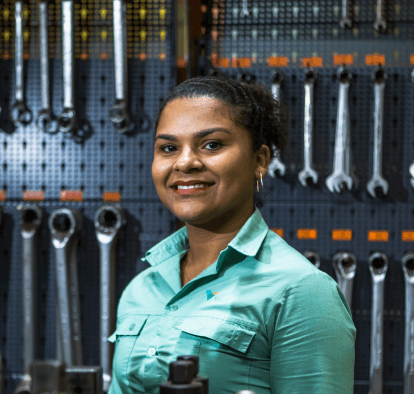 Female Vale's employee smiles to the photo. Behind her there are some tools