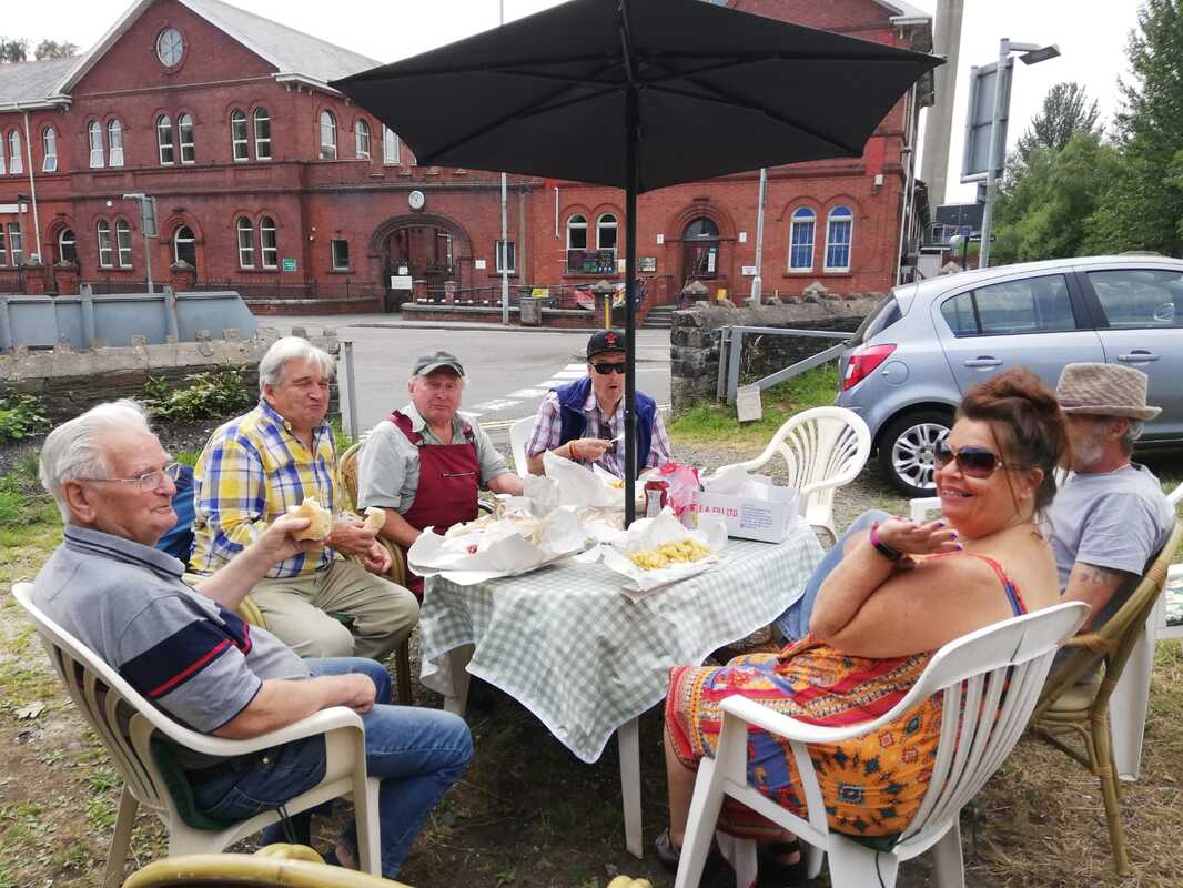 A group of people sitting around a table in front of Clydach operations