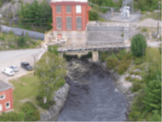 Photo of High Falls small hydropower plant II. A structure with bricks and windows on a bridge and underneath a river flowing.