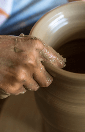 A hand molding a ceramic vase.