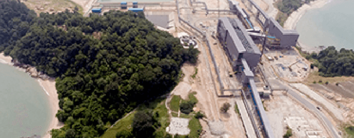 Imagem aérea do Terminal Teluk Rubiah. À esquerda há uma área de vegetação; embaixo é possível ver água e, no restante da imagem, uma área de operação, com grandes equipamentos.